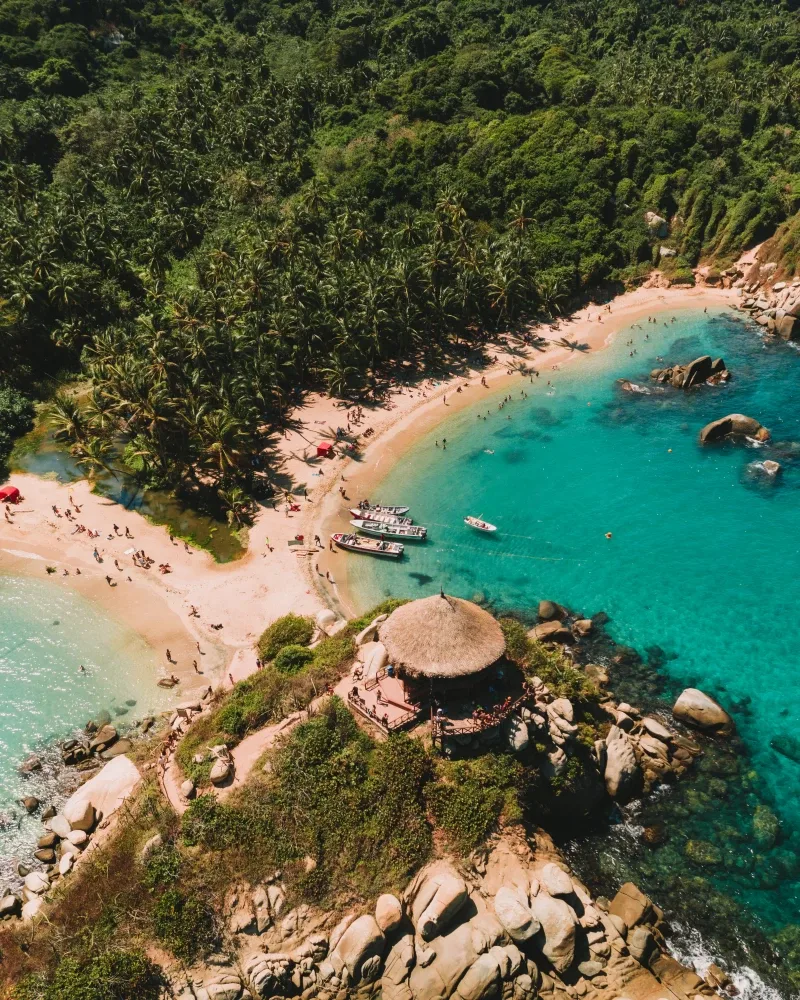Vista aérea de Cabo San Juan, Parque Tayrona: el mirador de palma sobre las rocas, dos playas de arena y agua turquesa.
